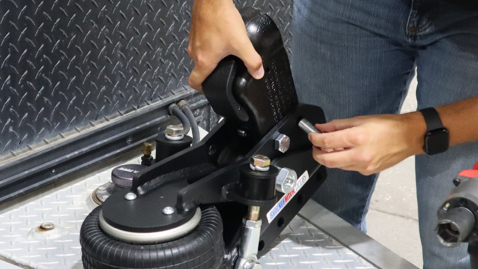 Hands aligning a Demco ball coupler and inserting attachment bolts into the Air Tongue Mount