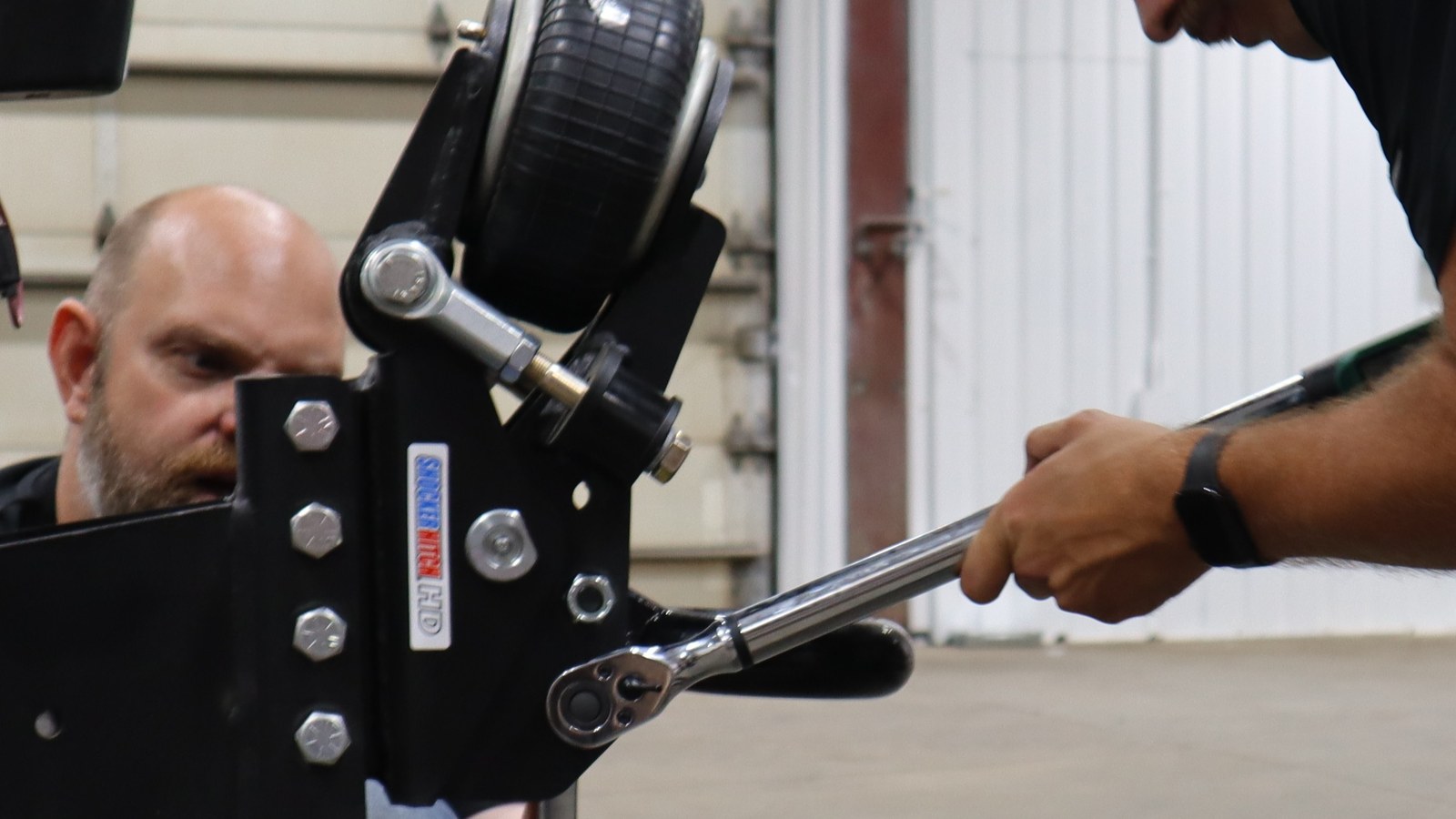Installer using a torque wrench to tighten pintle-ring bolts on a Shocker Air Tongue Mount